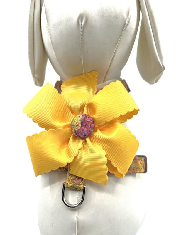 A yellow flower is attached to the back of a dog 's harness.