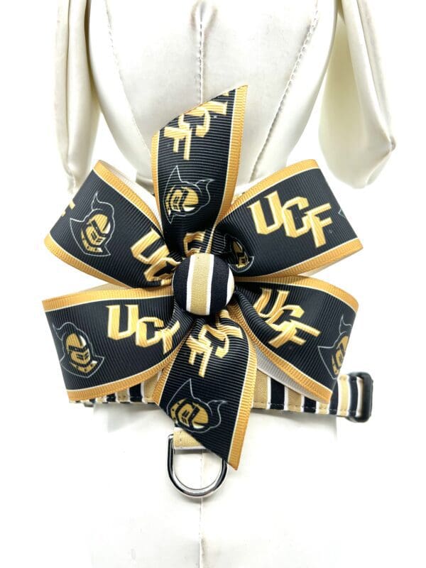 A dog collar with a black and gold bow.