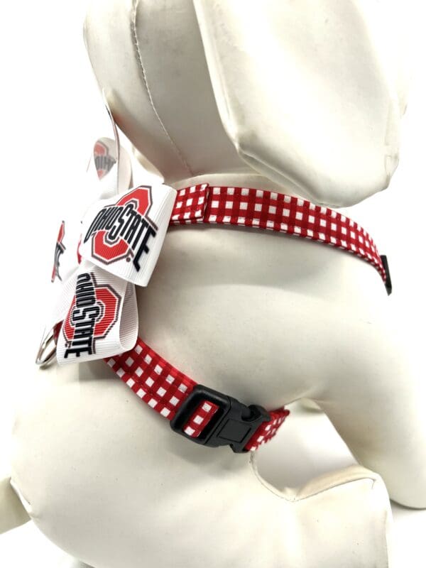 A dog wearing a harness with red and white polka dots.