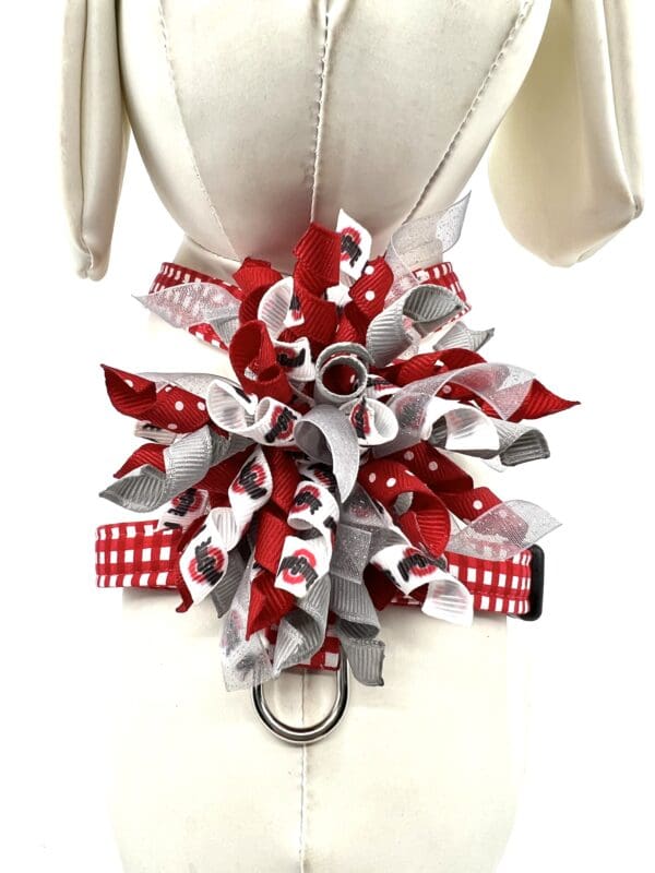 A red and white dog collar with a big bow