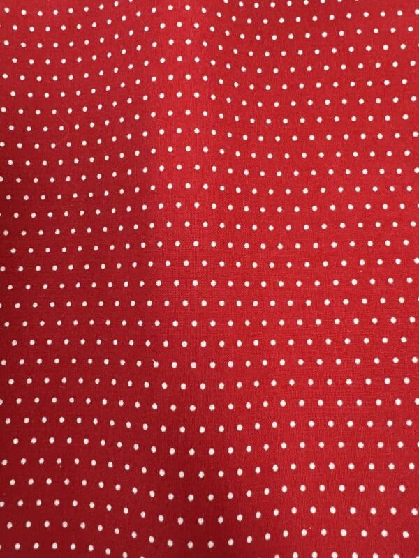 A red and white polka dot pattern on fabric.