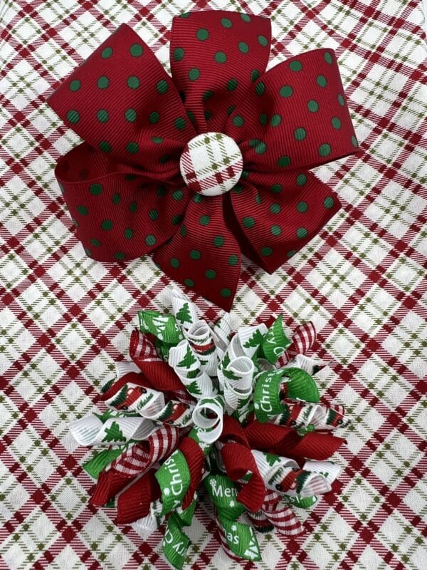 Two christmas bows on a plaid tablecloth.