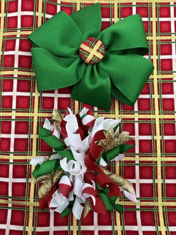 Two christmas bows on a plaid tablecloth.