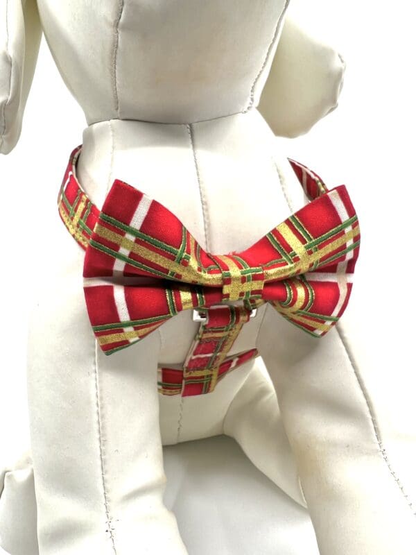 A dog wearing a red and green plaid bow tie.
