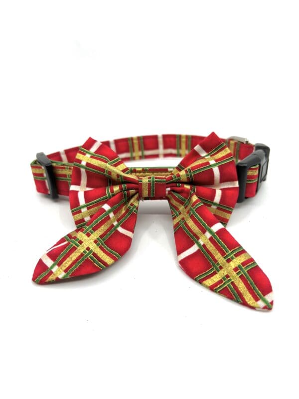 A red plaid dog collar with a bow on it.