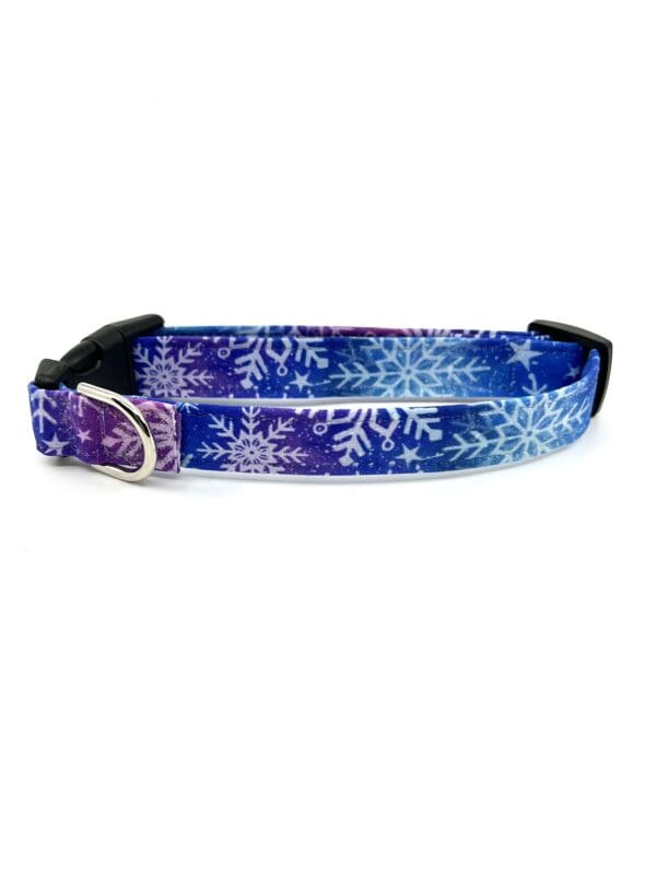 A purple and blue dog collar with snowflakes on it.