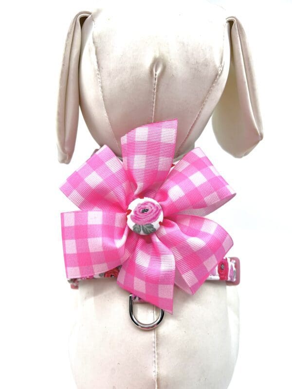 A pink dog collar with a pink bow on it.
