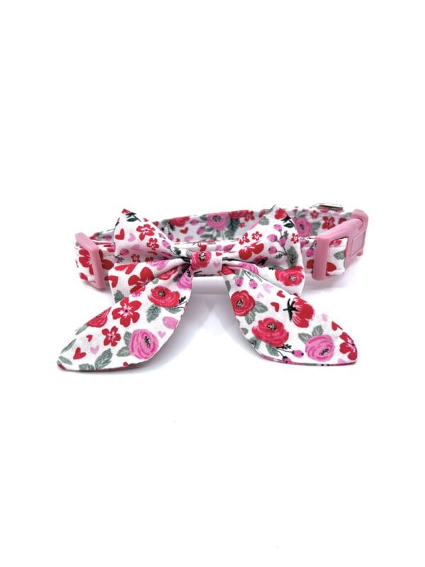A pink floral dog collar with a bow.