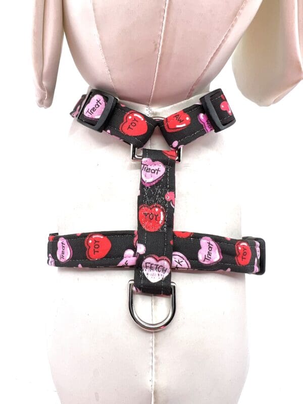 A mannequin wearing a dog harness with hearts on it.