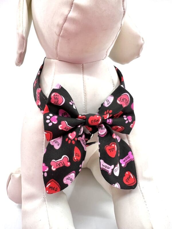 A stuffed dog wearing a bow tie with hearts on it.