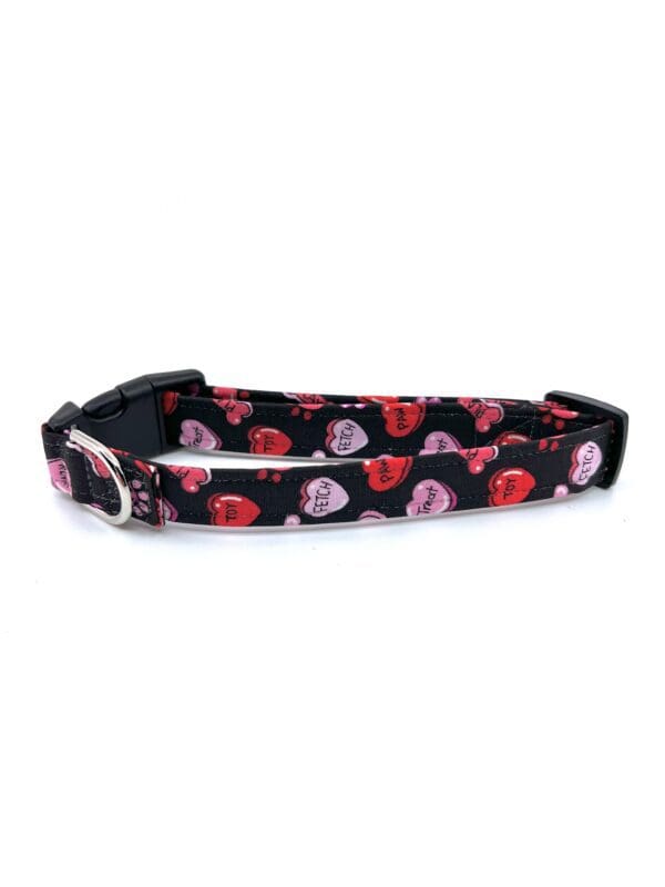 A black and pink dog collar with hearts on it.