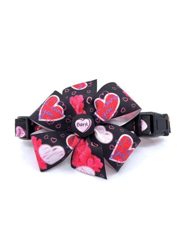 A black dog collar with a bow and hearts on it.