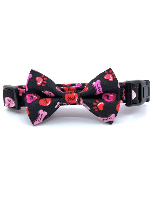 A black bow tie with pink hearts on it.