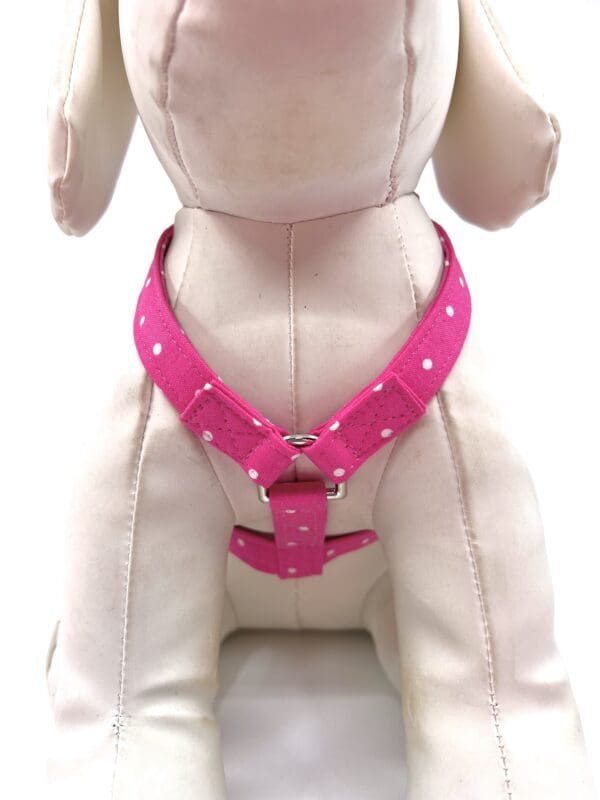 A stuffed dog wearing a pink harness.