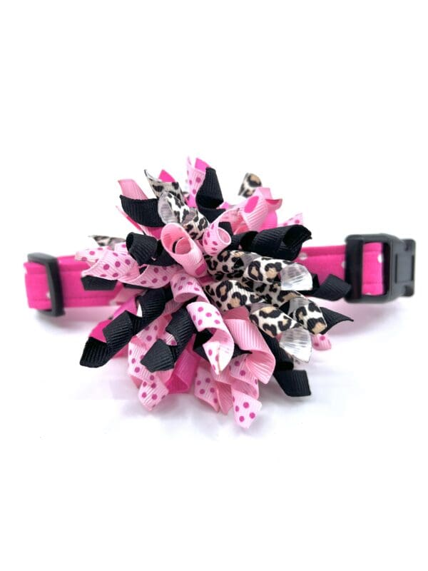 A pink and black pom pom dog collar.