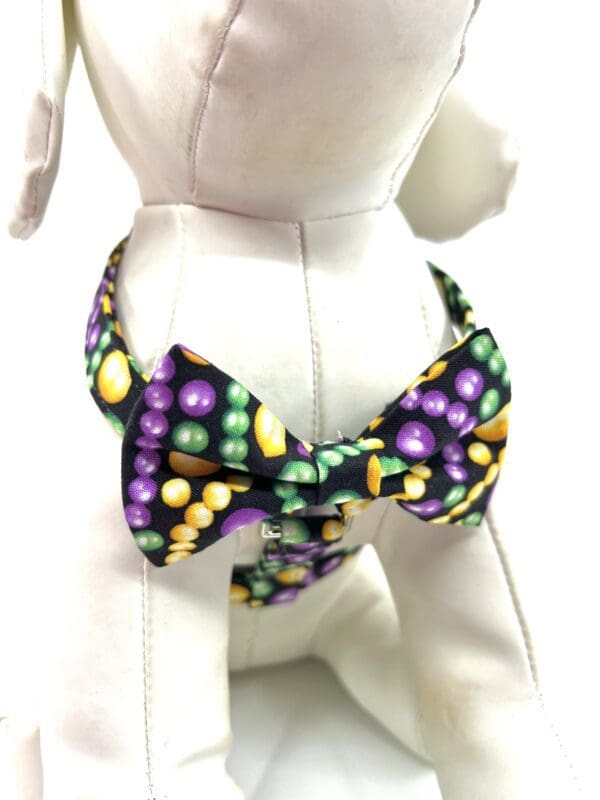 A dog wearing a purple and green bow tie.