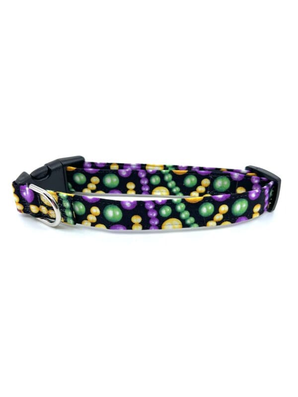 A purple and green mardi gras dog collar with a black buckle.