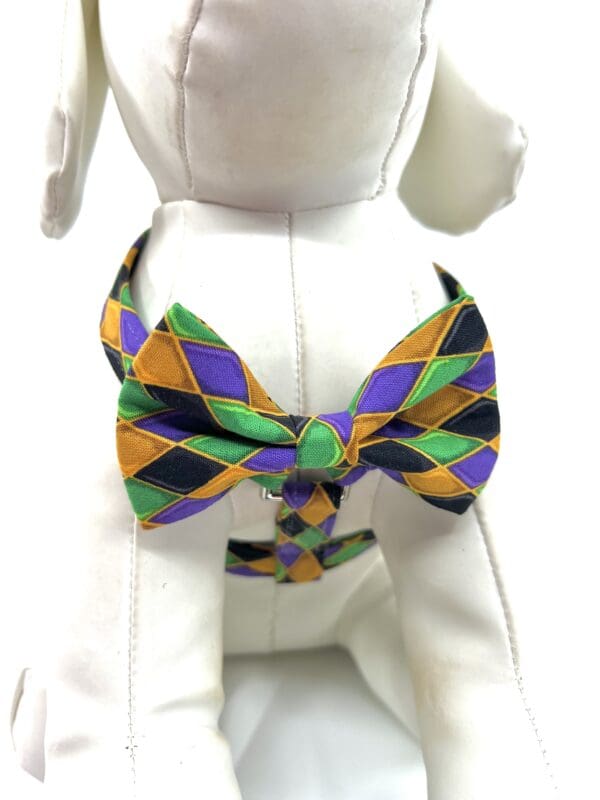 A dog wearing a purple and green bow tie.